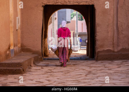 Ksar Elkhorbat, Maroc. Jeune femme prenant son eau pichets à la fonction d'un robinet d'eau à l'extérieur de la Casbah. Banque D'Images