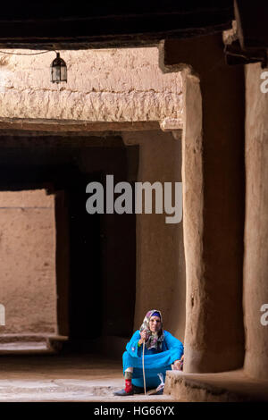 Ksar Elkhorbat, Maroc. Femme berbère Amazigh se reposant dans passage de la Casbah. Banque D'Images