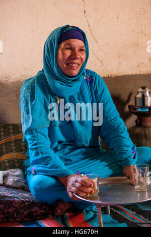 Ksar Elkhorbat, Maroc. Berbère Amazigh d'âge moyen femme à boire le thé dans son salon. Banque D'Images