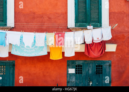 Séchage de blanchisserie de couleur vive en face d'une charmante maison rouge vif sur l'île de Procida, Italie Banque D'Images