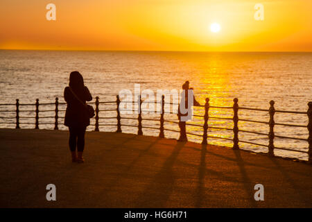 Blackpool, Lancashire, Royaume-Uni. 5Th Jan, 2017. Météo britannique. Coucher du soleil glorieux et la mer est calme car les gens à pied le long de la promenade, profitant de la dernière du soleil sur un jour d'hiver très froid. Credit : Mediaworld Images/Alamy LIve News Banque D'Images