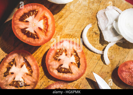 Photo de quelques tranches de tomate et l'oignon sur une planche à découper en bois Banque D'Images