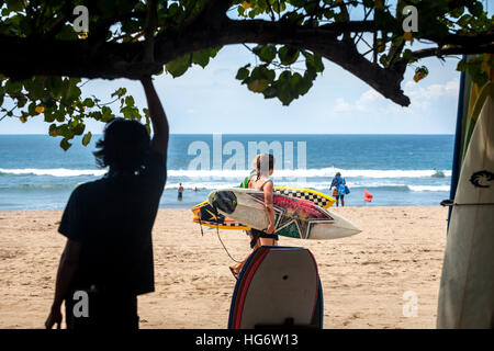 Femmes marchant sur la plage, portant des planches de surf à Kuta Beach, Kuta, Badung, Bali, Indonésie. Banque D'Images