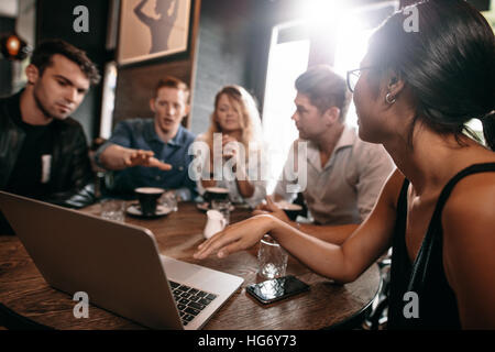 Jeunes amis looking at laptop au café et discuter. Les jeunes avec coffre à café. Banque D'Images