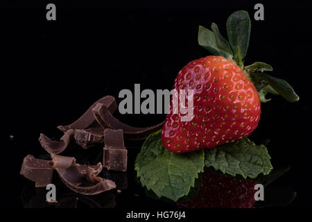 Libre de fraise avec les feuilles de menthe et de chocolat sur fond noir Banque D'Images