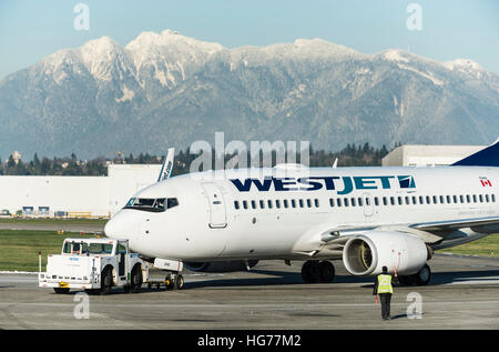 Boeing 737-700 de Westjet sur le macadam remorqué par un ralentissement, l'Aéroport International de Vancouver Banque D'Images