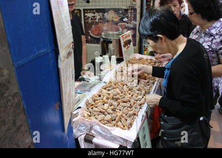 Une femme achète des fruits de mer séchés à un vendeur de rue à Hong Kong, Chine Banque D'Images