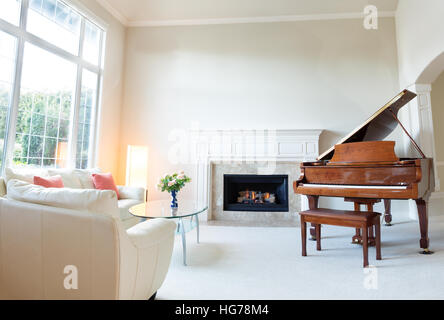 Jour lumineux du voyant en salle de séjour avec cheminée, piano et blanc canapé en cuir. Banque D'Images