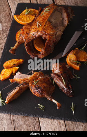 Canard rôti en tranches oranges et gros plan sur une plaque en ardoise noire sur la table verticale. Banque D'Images