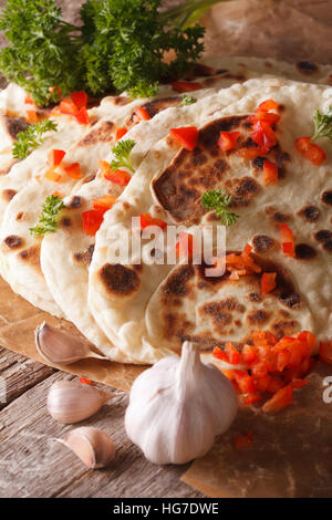 Pain naan indien avec de l'ail et poivre macro sur la table. vertical Banque D'Images
