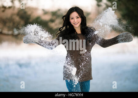 Funny Girl sweater provoque de la neige. Snow se brise dans l'air autour. Elle rit joyeusement. Banque D'Images