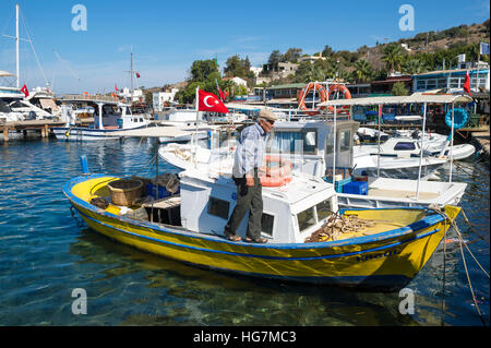 BODRUM, TURQUIE - 10 octobre 2016 : pêcheur turc promenades le long de son bateau traditionnel dans la ville touristique de Gumusluk. Banque D'Images