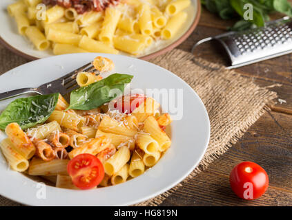 Servir les pâtes avec la sauce tomate et le parmesan sur la table en bois. Banque D'Images