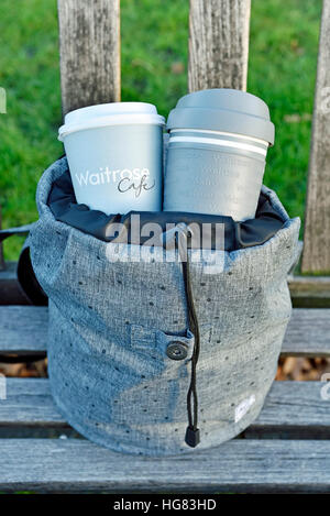 Waitrose emporter jetables et réutilisables tasse à café et tasse de voyage en sac à dos gris urbain intelligent sur banc de parc Central London Banque D'Images