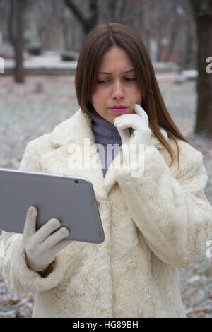 Jeune fille dans le parc à la tablette à Banque D'Images