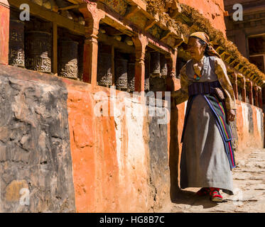 Femme autochtone à marcher le long du mur Mani et tourner les roues de prière, Kagbeni, Mustang, Népal Banque D'Images