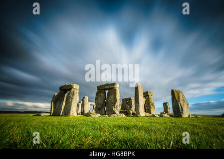 Stonehenge lors d'une journée hivernale ensoleillée et venteuse. Ruines anciennes dans le Wiltshire, en Angleterre, pas de gens ou de touristes. Herbe verte au premier plan, nuages en mouvement. Banque D'Images