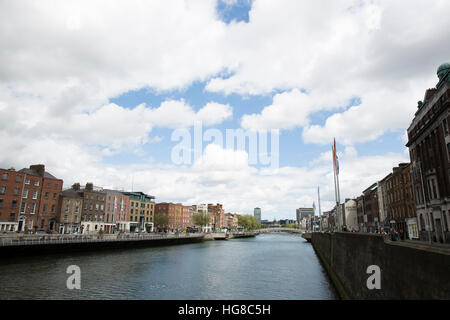 Ha'penny Bridge sur la rivière Liffey au milieu des bâtiments contre ciel nuageux Banque D'Images