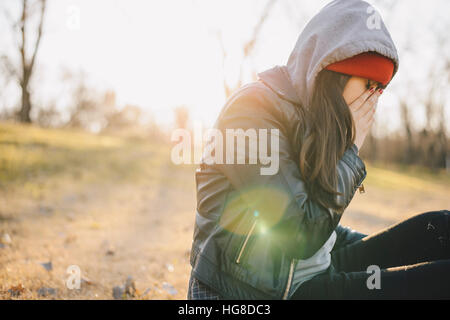 Sad woman sitting on field against sky Banque D'Images
