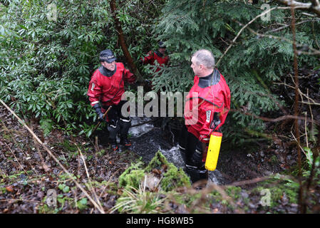 Les membres de l'Écosse de la police l'unité de police maritime vérifiez les étangs et cours d'eau dans les bois et champs proches de la scène d'une maison en feu à Milngavie, Merville, qui a coûté la vie de Cameron Logan. Banque D'Images