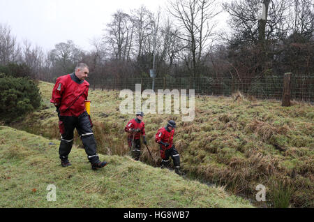 Les membres de l'Écosse de la police l'unité de police maritime vérifiez les étangs et cours d'eau dans les bois et champs proches de la scène d'une maison en feu à Milngavie, Merville, qui a coûté la vie de Cameron Logan. Banque D'Images