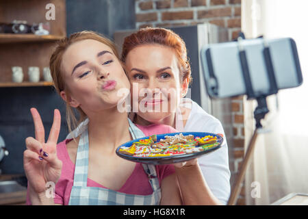 Mère et fille en maintenant la plaque selfies avec Christmas Cookies Banque D'Images