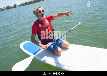 En contemplant la nature attractive mature rider assis sur paddle board Banque D'Images