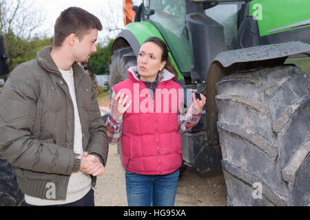 Jolie femme vendant tout nouveau tracteur pour agriculteur débutant Banque D'Images