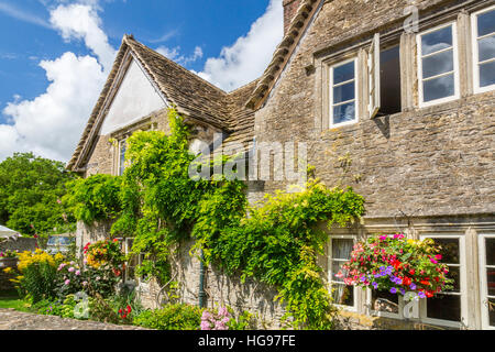 Une petite maison en pierre avec des toits de tuiles de pierre couverte de glycine dans le village de Lacock, Wiltshire, England, UK Banque D'Images