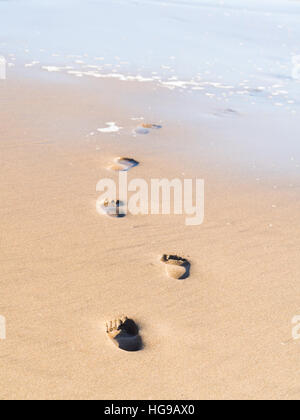 Des empreintes de pas entrer dans la mer sur une plage de Namibie. Banque D'Images