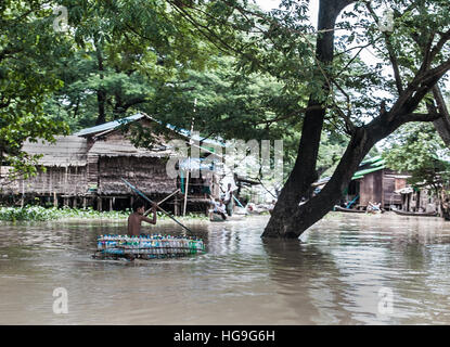 Un local jeunes voyages par un bateau fait de bouteilles de plastique durant les inondations dans le delta de l'Irrawaddy, Myanmar Banque D'Images