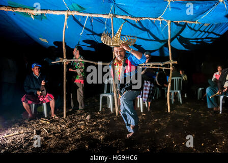 Un aîné portant une danse traditionnelle en tenue de chambre, dans un fond d'hommes jouant des instruments percussifs à Rote Island, à Nusa Tenggara est, Indonésie. Banque D'Images