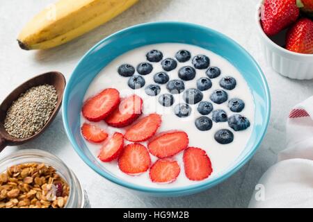 Smoothie aux fruits yaourt bol avec des fraises et des bleuets. Pot de graines de chia, granola maison, frais et fraises bananes Banque D'Images