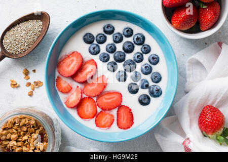 Smoothie aux fruits yaourt bol avec des fraises et des bleuets. Pot de graines de chia, granola maison, frais et fraises bananes Banque D'Images