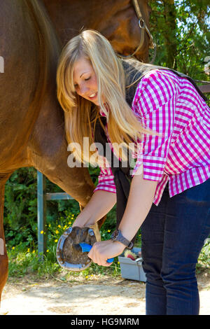 Jeune femme en raclant de sabot d'un cheval Banque D'Images