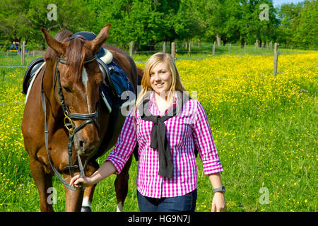 Teenage girl walking horse in field Banque D'Images