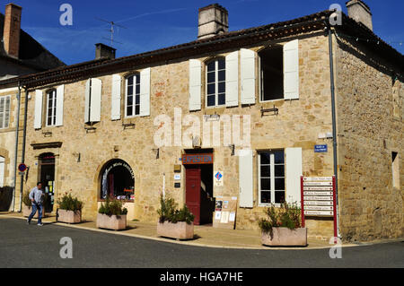 Homme marchant passé Office de tourisme et de coiffeurs shop à Aignan, France. Banque D'Images