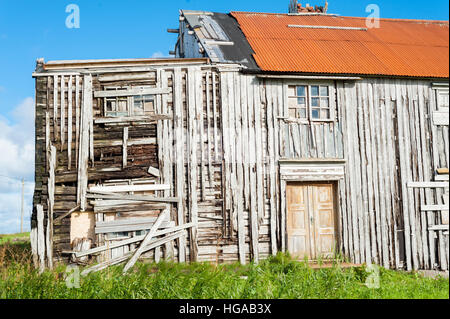 Vue latérale d'une vieille maison en bois à l'abandon et au toit rouge et casse de murs extérieurs Banque D'Images