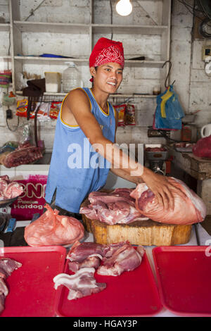 Un jeune garçon philippin prépare le porc à la vente à la marché public de Barretto, l'île de Luzon, aux Philippines. Banque D'Images