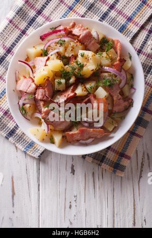 La salade de pommes de terre aux lardons et oignons dans un bol. vertical vue d'en haut Banque D'Images