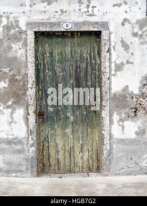 Vieille porte au numéro 8. L'écaillage de la peinture et une poignée de rouille marquer les années sur cette vieille porte de planches situé dans un mur en ruine. Banque D'Images