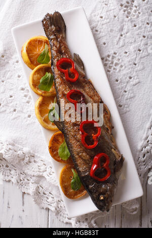 La truite grillée au citron gros plan sur une assiette sur la table. vertical vue d'en haut Banque D'Images