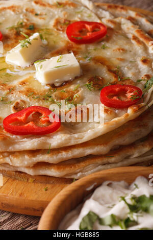 Paratha Placez indiennes avec le beurre et les herbes macro sur la table verticale. Banque D'Images