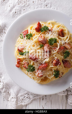 Les pâtes italiennes carbonara avec bacon et parmesan close-up sur une plaque verticale Vue de dessus. Banque D'Images