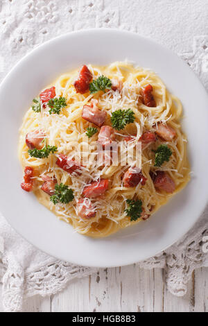 Les pâtes à la carbonara avec du bacon et parmesan close-up sur une plaque verticale Vue de dessus. Banque D'Images