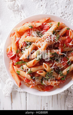 Pâtes penne arrabiata de fromage Parmesan sur un gros plan de la plaque verticale Vue de dessus. Banque D'Images