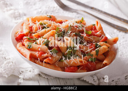 Arrabbiata pâtes chaudes avec du parmesan et des herbes gros plan sur une plaque horizontale. Banque D'Images