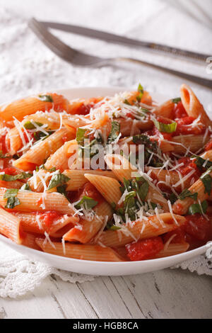 Arrabbiata pâtes avec du parmesan et des herbes gros plan sur une plaque verticale sur la table. Banque D'Images