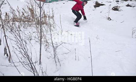 Snowboard garçon automne rouler dans la neige avec les vacances sport hiver Banque D'Images