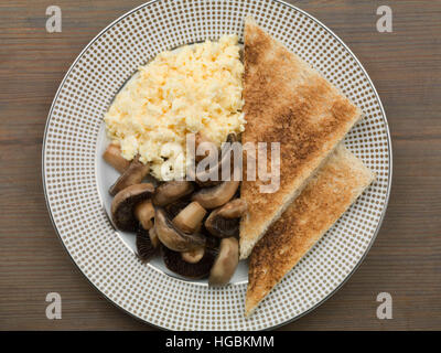 Un petit-déjeuner sain d'oeufs brouillés Champignons et pain grillé servi sur un plateau d'une télévision jeter la composition avec aucun peuple un régime alimentaire contrôlé en calories Banque D'Images